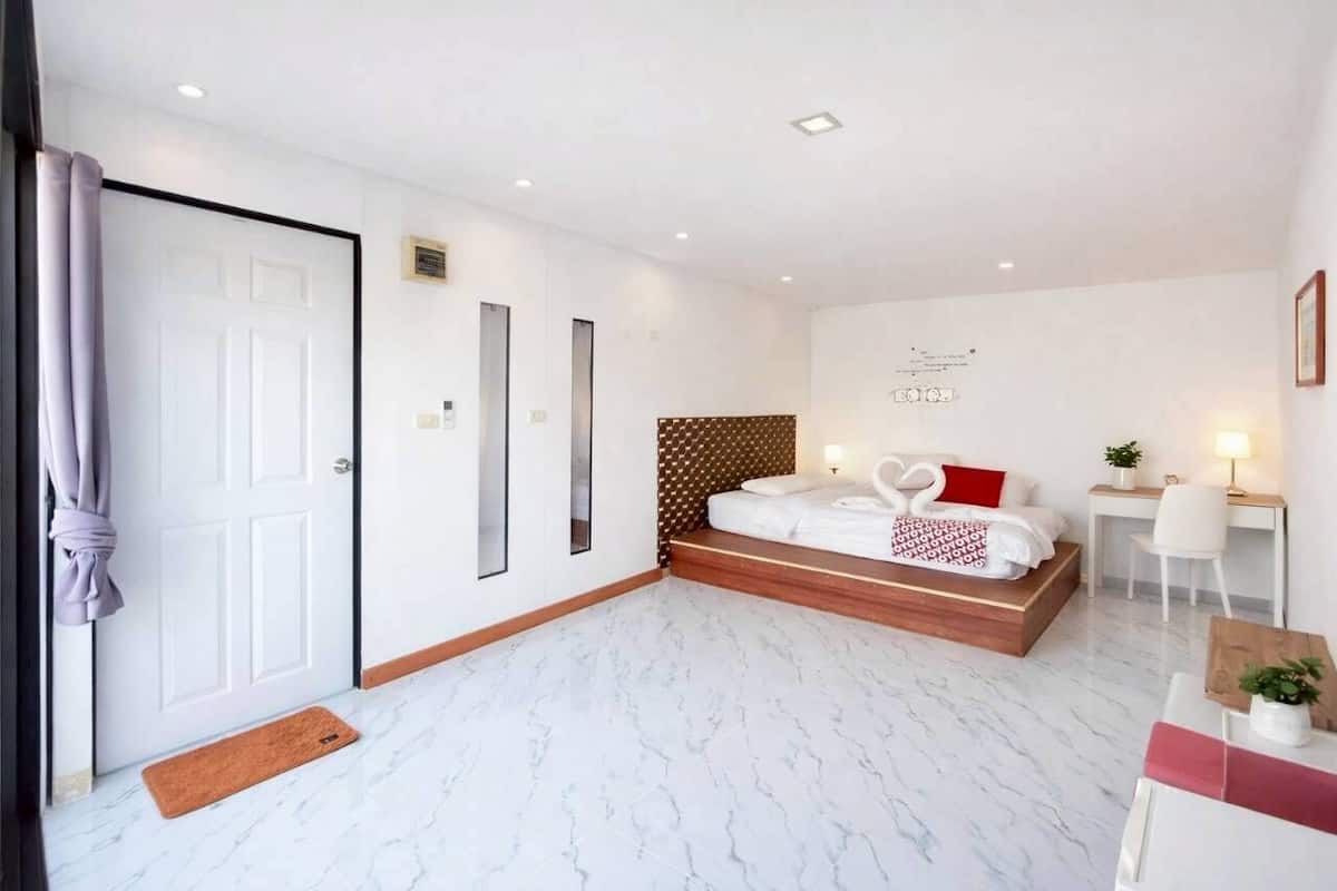 A hotel room with a bed, bedside table, lamp, and a wall-mounted artwork.