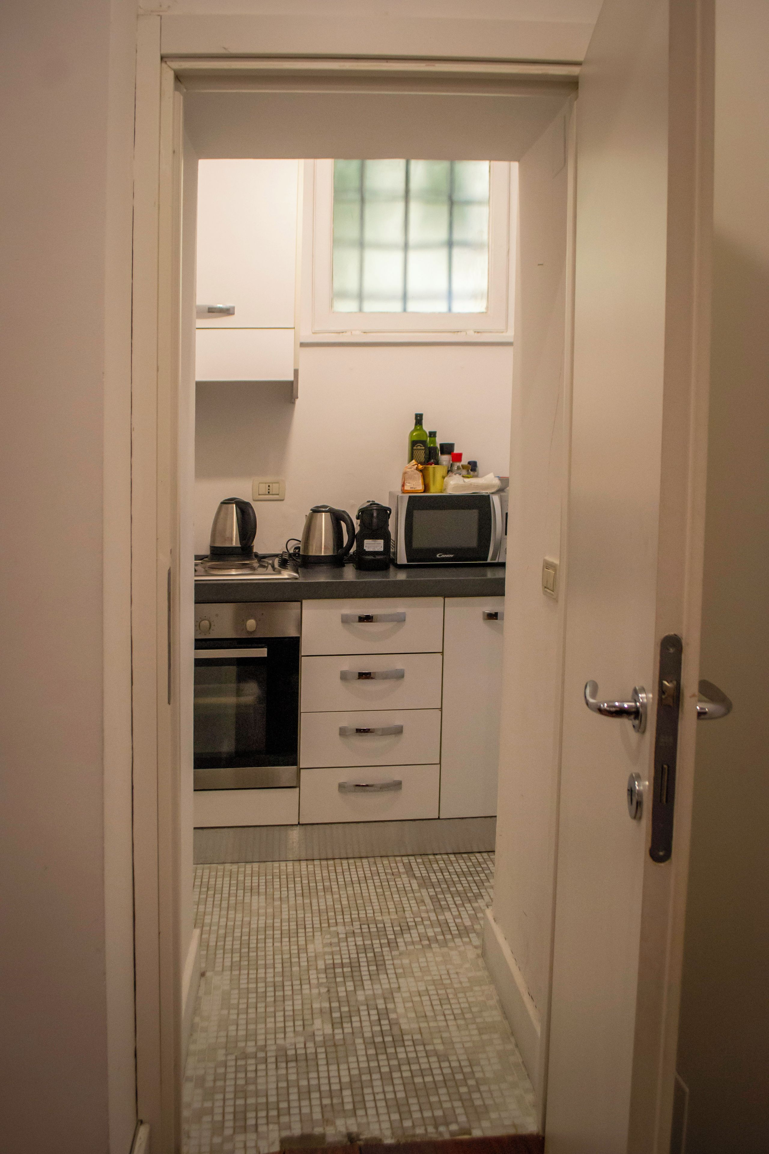 A compact kitchen with a microwave, kettle, and oven.