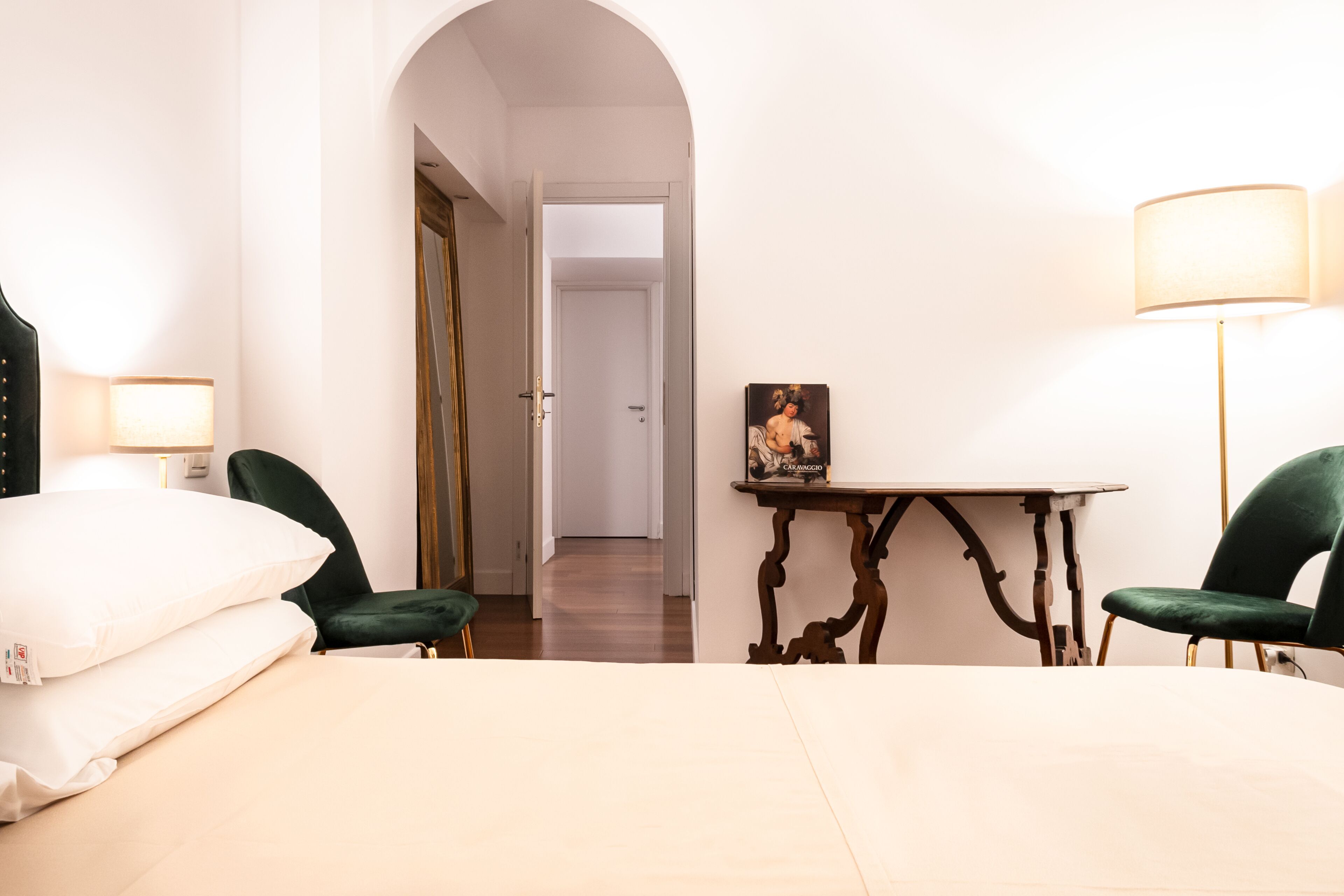 A hotel room with a bed, two chairs, a table, a lamp, and a picture on the wall.