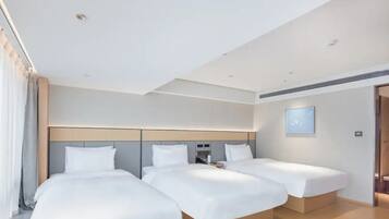 A hotel room with two beds, a headboard, a bedside table, and a wall-mounted light.