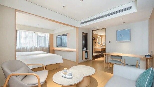 Ett hotellrum med en säng, en soffa, en stol, ett skrivbord och en tv.