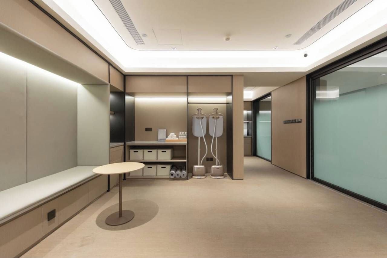 A modern, well-lit hallway with a bench, a table, and a storage unit with hanging items.