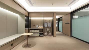 A modern, well-lit hallway with a bench, a table, and a storage unit with hanging items.