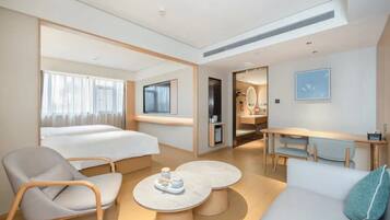 A hotel room with a bed, a sofa, a chair, a desk, and a TV.