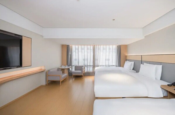 A hotel room with a large bed, a TV, a desk, and a chair.