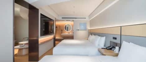 A hotel room with two beds, a bathroom, a TV, and a bedside table with a phone.