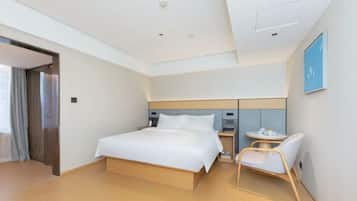 A modern hotel room with a large bed, bedside tables, a chair, and a small table with a cup and saucer.
