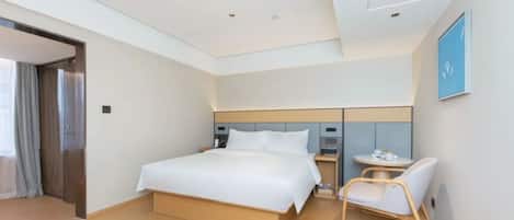 Una habitación de hotel moderna con una cama grande, mesitas de noche, una silla y una pequeña mesa con una taza y un plato.