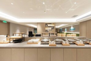 A modern buffet setup with multiple serving stations, a central display area, and a clean, well-lit environment. - Ji Hotel (Beijing)