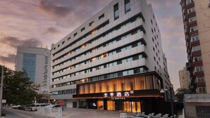 Ett hotell med flera våningar, en modern fasad, stora fönster och en framträdande entré med en skylt.