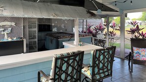 Ein Außenbereich mit Terrasse, überdachter Sitzecke, Grill und Topfpflanzen.
