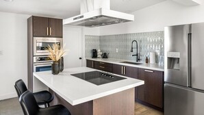A modern kitchen with a central island, stainless steel appliances, and a patterned backsplash. - Kalima Sky - Golf Cart, Pool/Spa, Gym, Corner Lot (La Quinta)