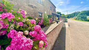 A rustic stone building with a paved road in front. - 16th Cent,6 bed house,15 People (Monmouthshire)