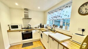 A compact kitchen with a microwave, oven, sink, and toaster.