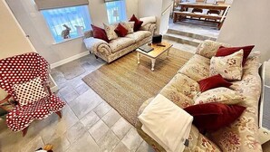 A living room with a sofa, armchair, and coffee table. There is a staircase leading to an upper level.