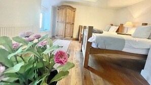 A bedroom with a wooden bed, a nightstand, a lamp, and a window.