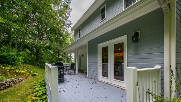 Ein Haus mit überdachter Veranda, einer Steinmauer und einem Garten.