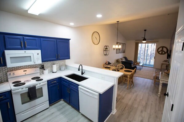 Een moderne keuken met blauwe kastjes, witte aanrechtbladen en een centraal eiland.