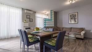 Un soggiorno moderno con un tavolo da pranzo, sedie, un divano e un pannello decorativo.