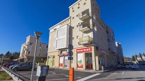 Un edificio a più piani con un cartello che indica 'market', un parcheggio pieno di auto e un cielo azzurro limpido.
