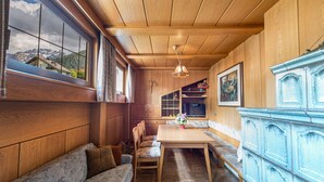 Een houten interieur met een eettafel, stoelen, een bankje en een kast.