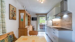Een kleine keuken met een houten kast, een eettafel en een televisie.