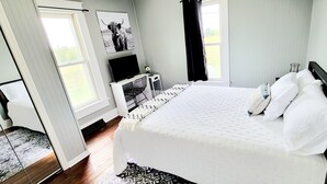 Une chambre à coucher avec un lit, une télévision, un bureau et une fenêtre.