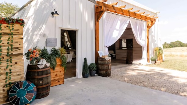 Un bâtiment de style rustique, évoquant une grange, avec une façade en bois, un porche couvert et une allée gravillonnée.
