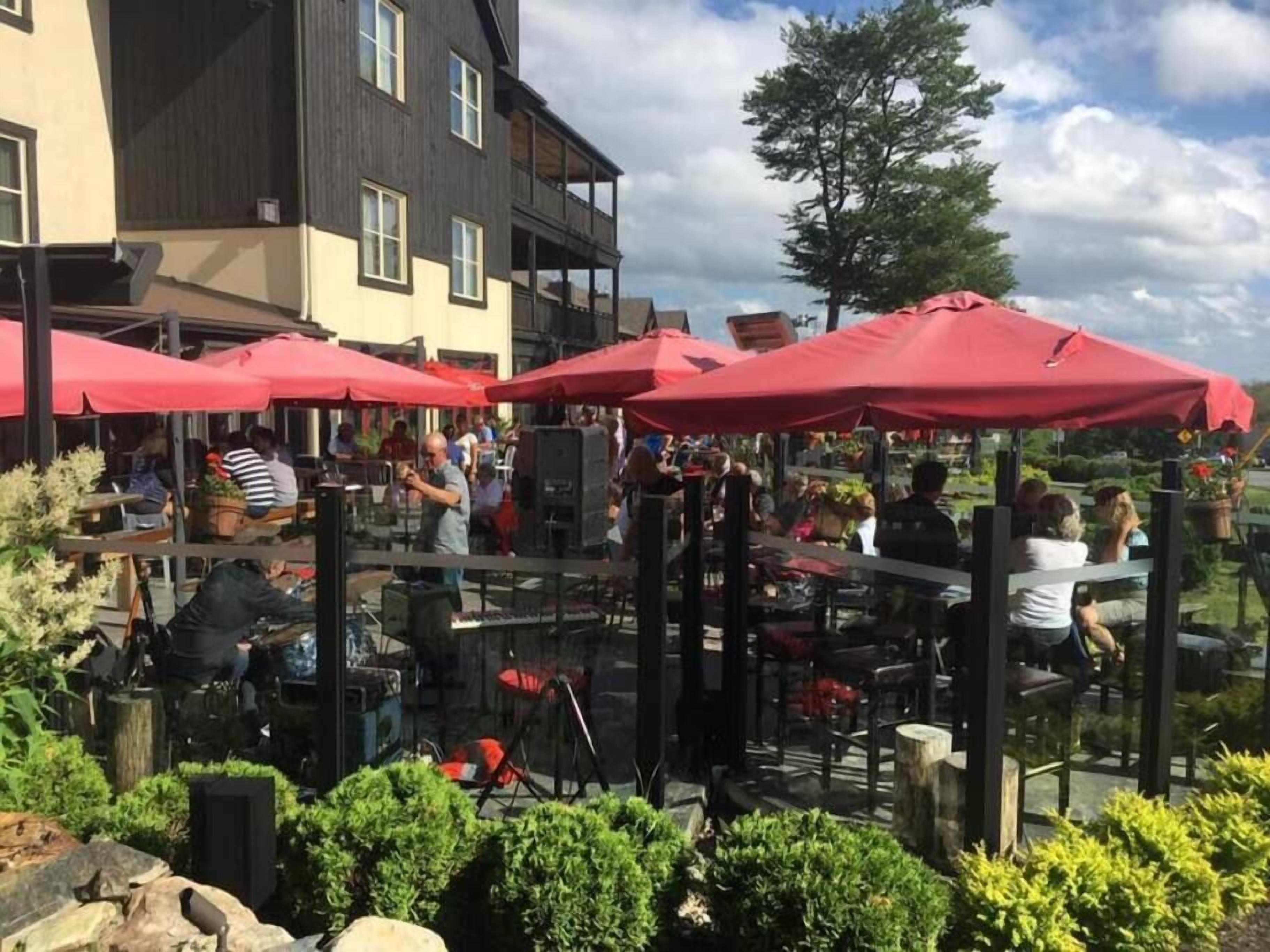 An outdoor patio area with red umbrellas, tables, and chairs.