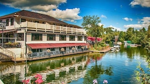 A riverside building with a balcony and outdoor seating area. - The Lighthouse - Access to the Lake (Magog)