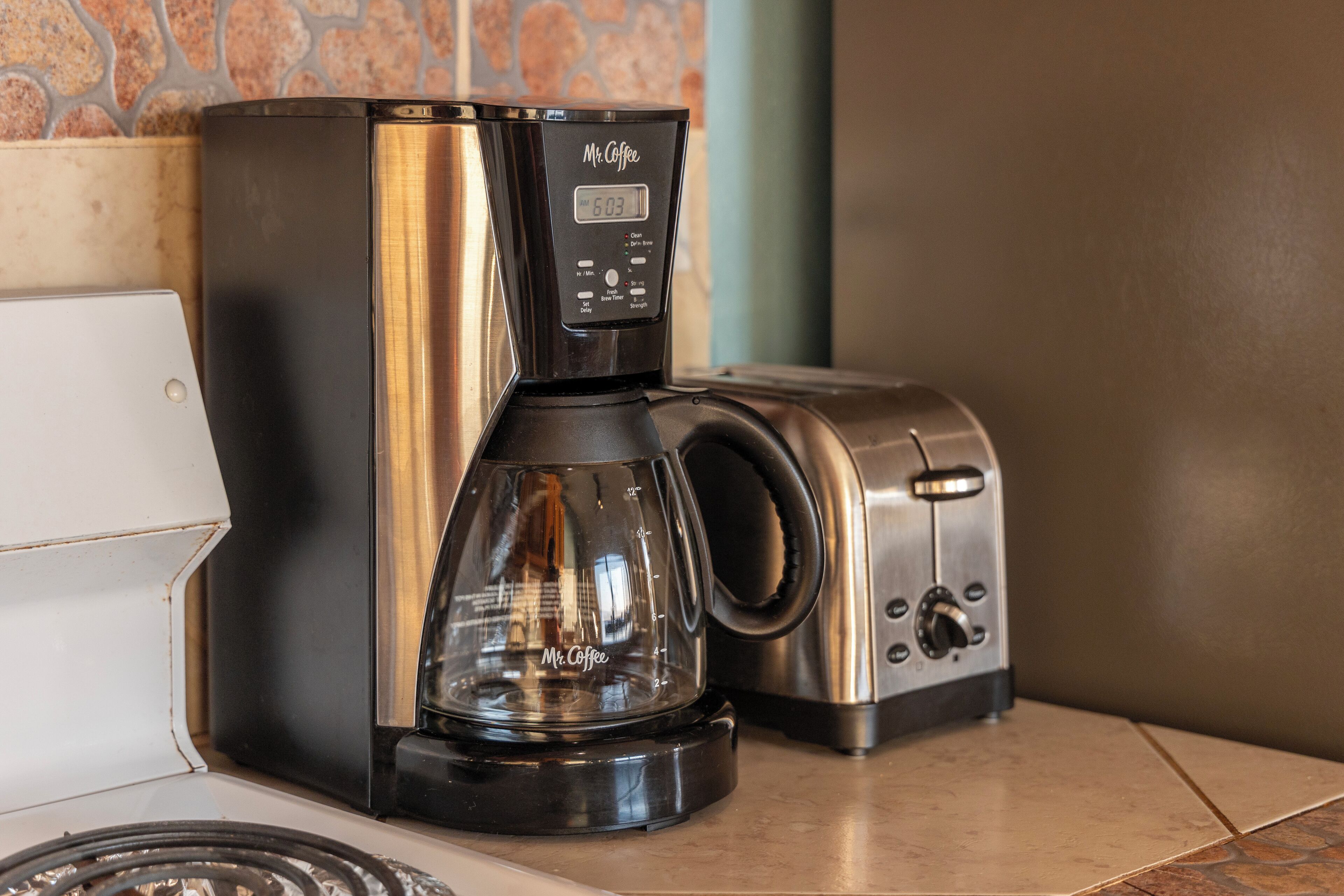 Een Mr. Coffee koffiezetapparaat met een digitaal display, een broodrooster en een keukentrap.