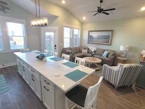 A modern kitchen with a central island, white cabinetry, and a dining area with a round table and chairs.