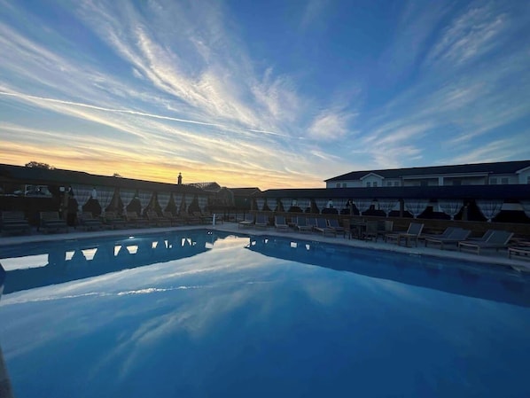 Una piscina con lettini e un edificio sullo sfondo.