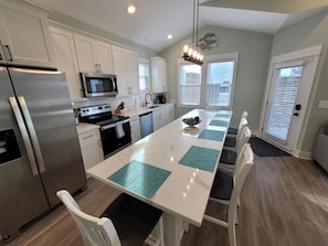 A modern kitchen with white cabinets, stainless steel appliances, and a central island with chairs.