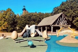 A playground with a slide, swings, and a small building.