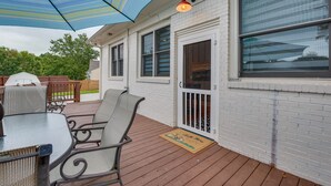 Une terrasse extérieure avec une table et des chaises, un grand parasol et une porte avec une fenêtre.