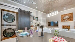 A modern kitchen with a dining area, including a large table set with plates, glasses, and a bowl. - Cozy + Modern Norcross Hideaway w/ Covered Porches (Norcross)