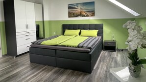 Une chambre à coucher moderne avec un lit, une table de chevet, une armoire et un tableau au mur.