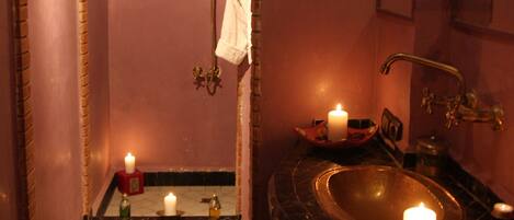 A bathroom with a brick archway, a sink, and two lit candles.