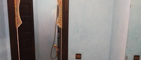 Ein Badezimmer mit einem Kupferspülbecken, einem Spiegel, einem Handtuchhalter und einer Duschkabine.