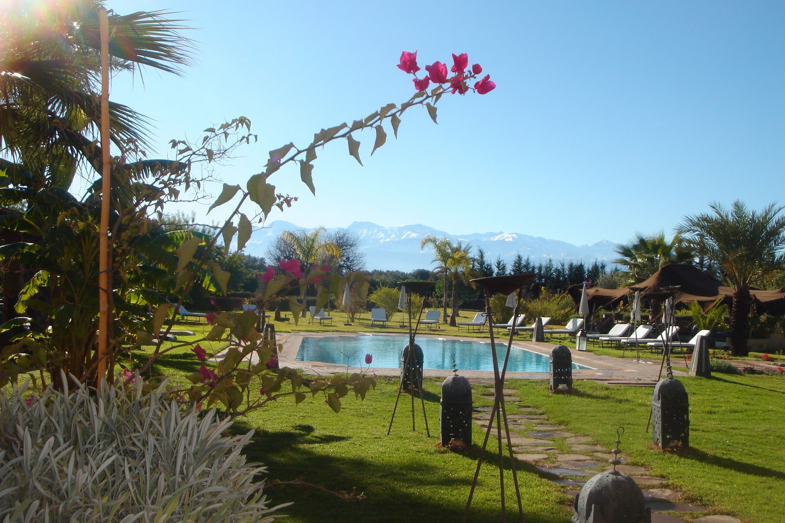 A pool area with lounge chairs and a view of mountains.