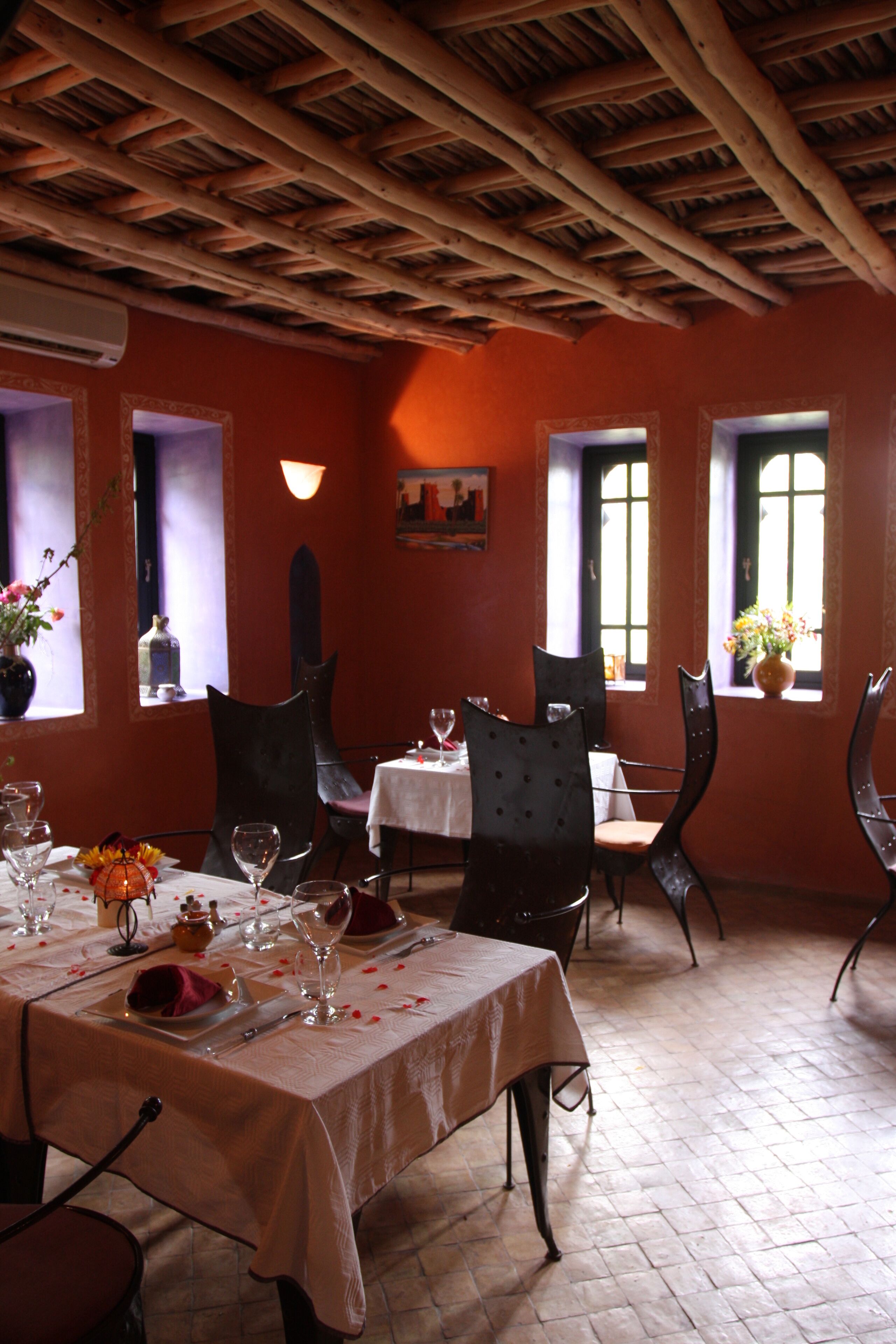 Un comedor con una mesa dispuesta para dos, con mantel blanco, dos sillas y un jarrón con flores.