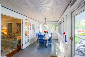 Relax in this spacious living area with a dining table, sofa, and large windows offering a view of the outdoors.