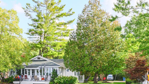 A gazebo with a covered porch and a dock extending into a calm pond. - The Red Geranium Cottage of Big White Fish Lake! (Pierson Township)