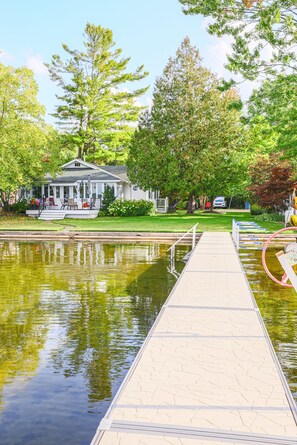 Relax on the serene lakeside dock, surrounded by lush trees and a charming gazebo with a shaded porch.