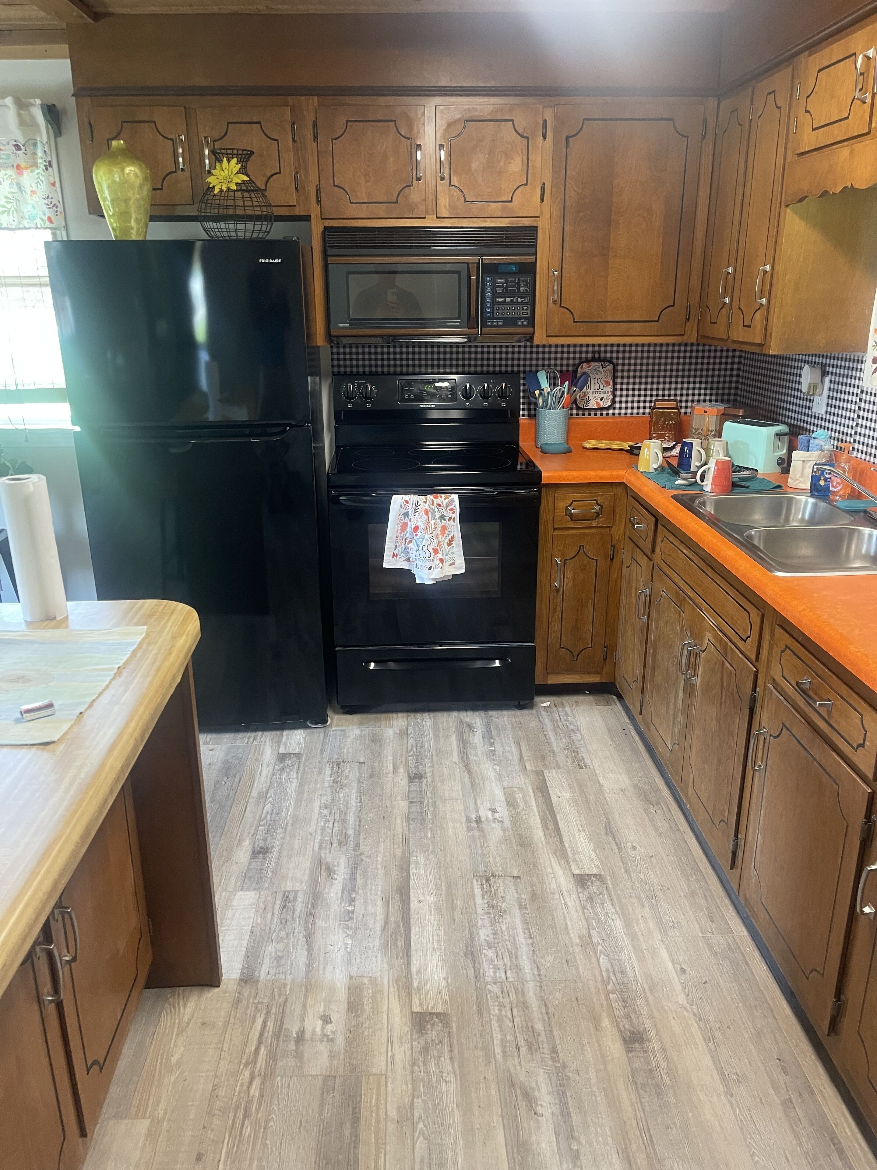 A kitchen with wooden cabinets, a black refrigerator, a microwave, and a stove.