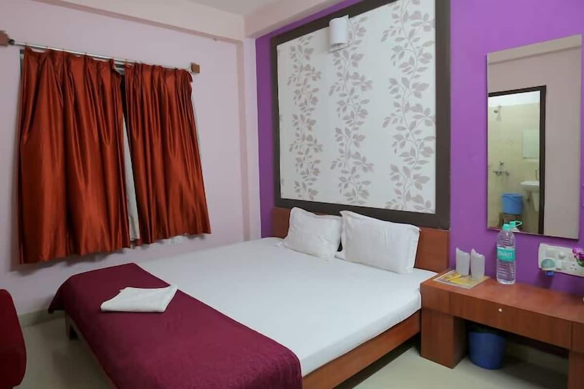 Ein Hotelzimmer mit Bett, Schreibtisch, Stuhl und einem Vorhangfenster.
