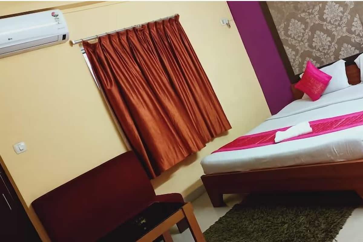 Ein Schlafzimmer mit Bett, Stuhl, Vorhang und einer Wand-Klimaanlage.