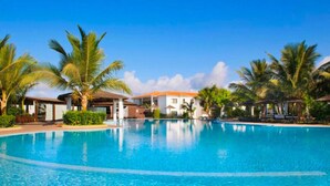 A clear blue swimming pool surrounded by palm trees and resort buildings. - VILLA TORTUGA BEACH RESORT (Sal)