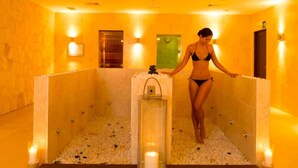 A spa room with a stone wall, a wooden bench, and a glass-enclosed hot tub with candles. - VILLA TORTUGA BEACH RESORT (Sal)